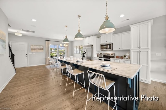 kitchen with pendant lighting, stainless steel appliances, a spacious island, and white cabinets