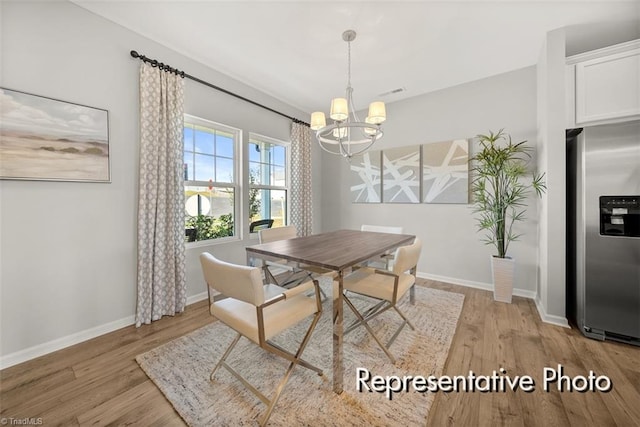 dining space featuring light wood-style floors, baseboards, and a notable chandelier