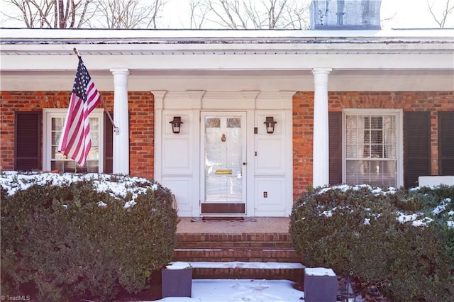 snow covered property entrance featuring a porch