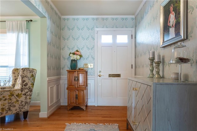 foyer entrance featuring a wealth of natural light, ornamental molding, and light hardwood / wood-style floors