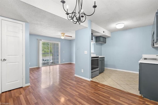 kitchen featuring light wood-type flooring, stainless steel electric range oven, and a textured ceiling