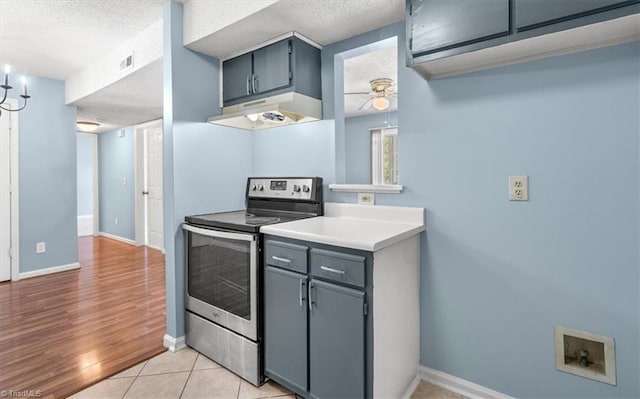 kitchen featuring stainless steel range with electric stovetop, a textured ceiling, light hardwood / wood-style floors, and gray cabinets