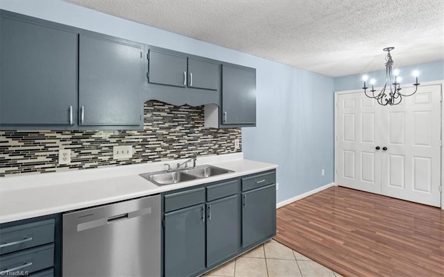 kitchen with pendant lighting, light wood-type flooring, stainless steel dishwasher, sink, and a notable chandelier