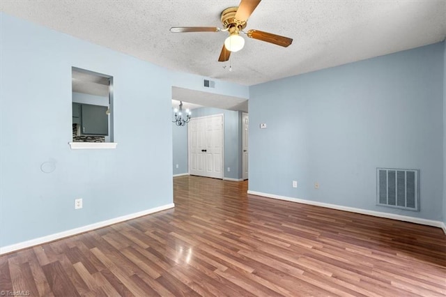 empty room with a textured ceiling, ceiling fan with notable chandelier, and hardwood / wood-style floors