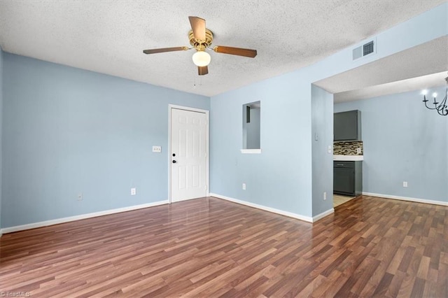 empty room with a textured ceiling, ceiling fan with notable chandelier, and dark wood-type flooring