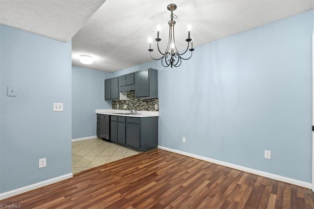 kitchen featuring hanging light fixtures, sink, a textured ceiling, light hardwood / wood-style flooring, and backsplash