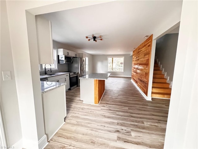 kitchen with light stone countertops, stainless steel appliances, light hardwood / wood-style flooring, and a kitchen island