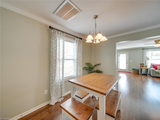 dining area featuring dark wood-type flooring, ornamental molding, and ceiling fan with notable chandelier