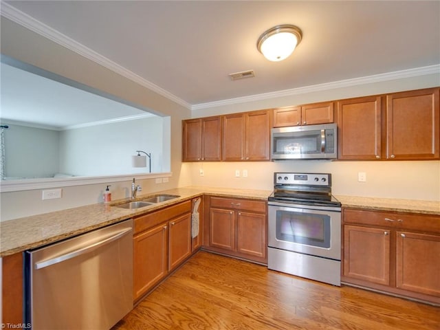 kitchen with sink, light wood-type flooring, appliances with stainless steel finishes, and ornamental molding