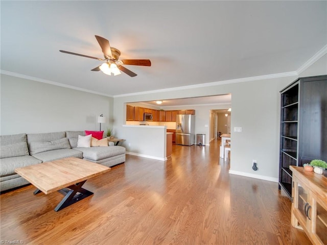 living room featuring ceiling fan, light hardwood / wood-style floors, and crown molding