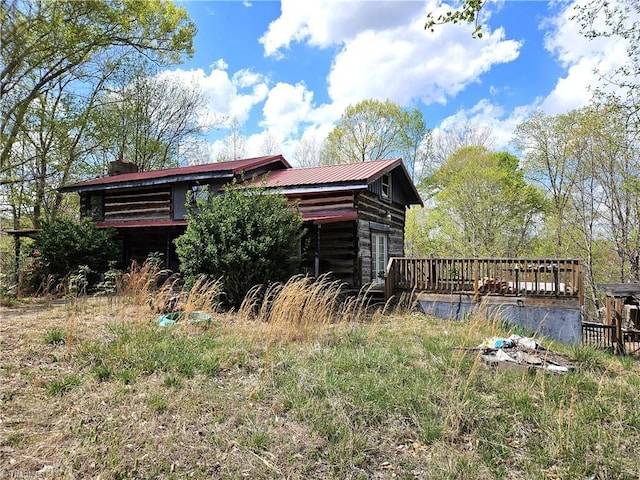 view of property exterior featuring metal roof and a wooden deck