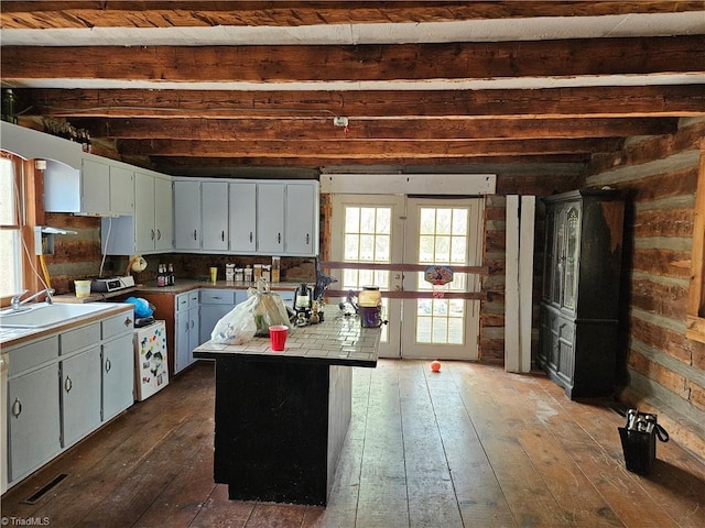 kitchen with light countertops, french doors, a center island, a sink, and dark wood-style floors