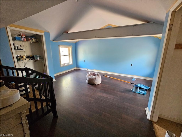bedroom with baseboards, lofted ceiling, a closet, and wood finished floors