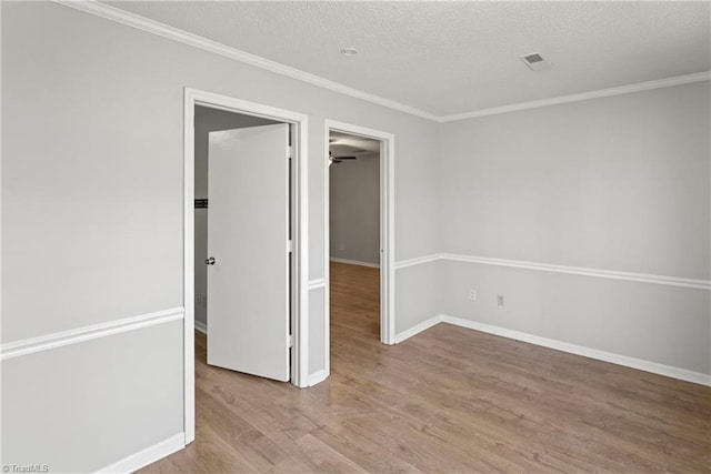 empty room with wood-type flooring, ornamental molding, and a textured ceiling