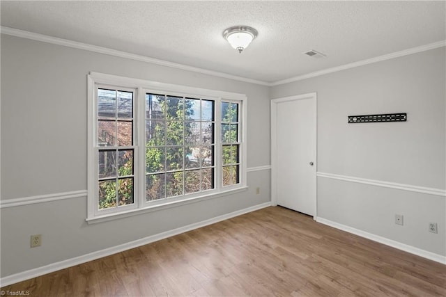 spare room with crown molding, wood-type flooring, and a textured ceiling