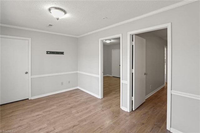 unfurnished room featuring light hardwood / wood-style flooring, ornamental molding, and a textured ceiling