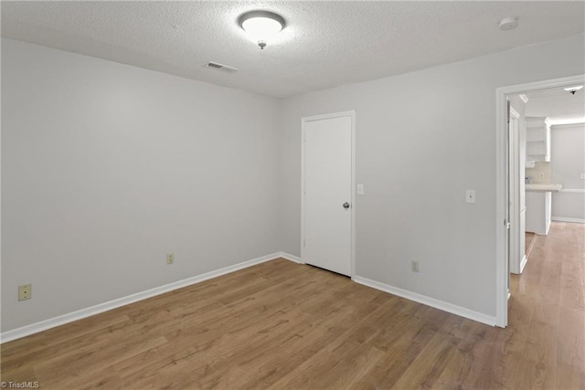 unfurnished room featuring a textured ceiling and light hardwood / wood-style floors