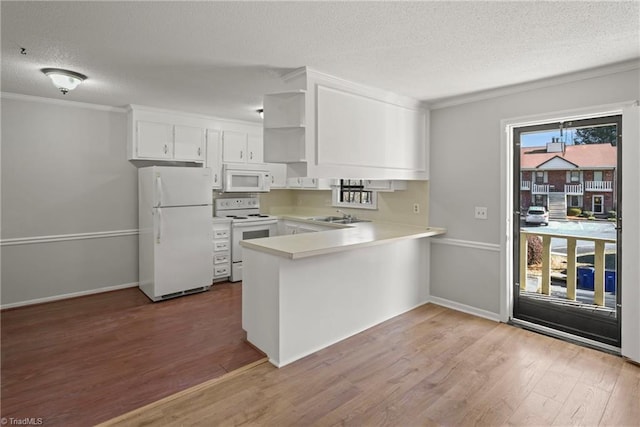 kitchen with a textured ceiling, light wood-type flooring, kitchen peninsula, white appliances, and white cabinets