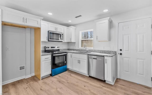 kitchen with sink, light stone countertops, white cabinets, and appliances with stainless steel finishes