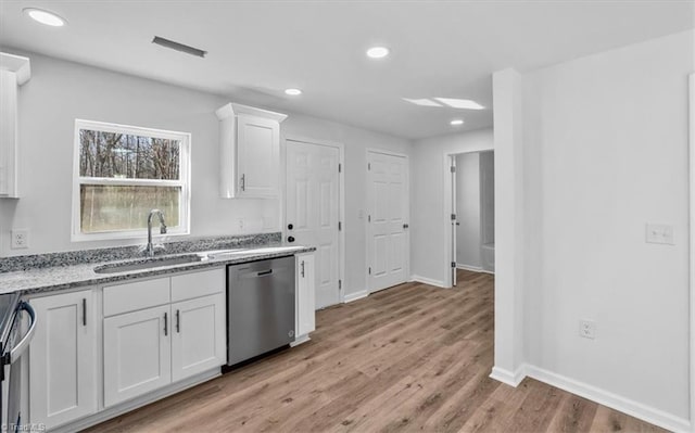 kitchen featuring sink, light stone counters, stainless steel dishwasher, light hardwood / wood-style floors, and white cabinets