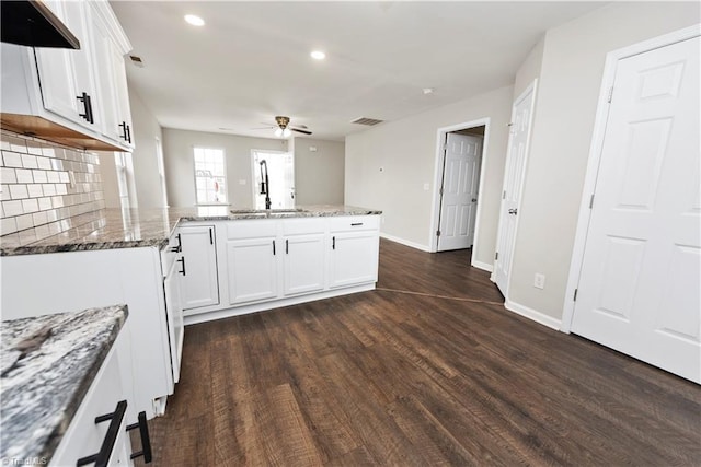 3217 N Ohenry Blvd, Greensboro, NC 27405 - kitchen featuring dark wood-type flooring, a ceiling fan, a sink, a peninsula, and light stone countertops