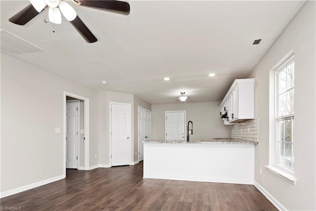 3217 N Ohenry Blvd, Greensboro, NC 27405 - kitchen featuring dark wood finished floors, white cabinets, a peninsula, and light stone counters