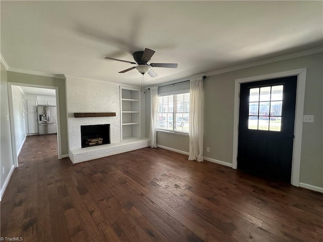 unfurnished living room with ceiling fan, dark wood-type flooring, crown molding, a brick fireplace, and built in shelves