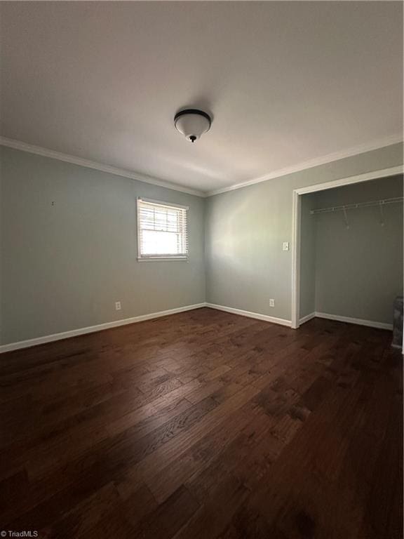 unfurnished bedroom with dark wood-style floors, a closet, baseboards, and crown molding