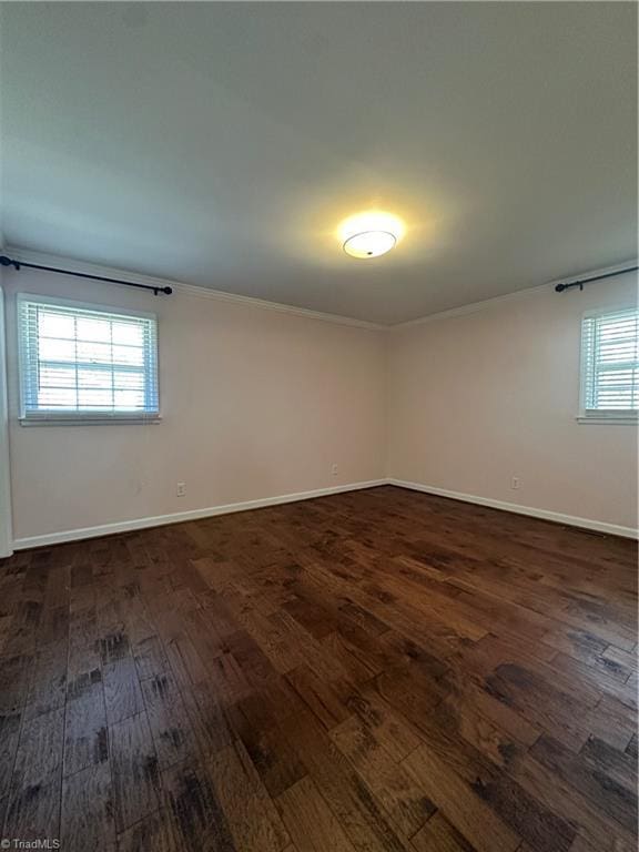 spare room with ornamental molding, dark wood-style flooring, and baseboards