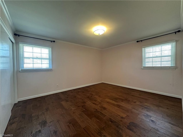 spare room featuring baseboards, dark wood-style flooring, and crown molding