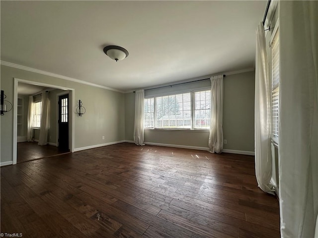 spare room featuring ornamental molding, dark wood-style flooring, and baseboards