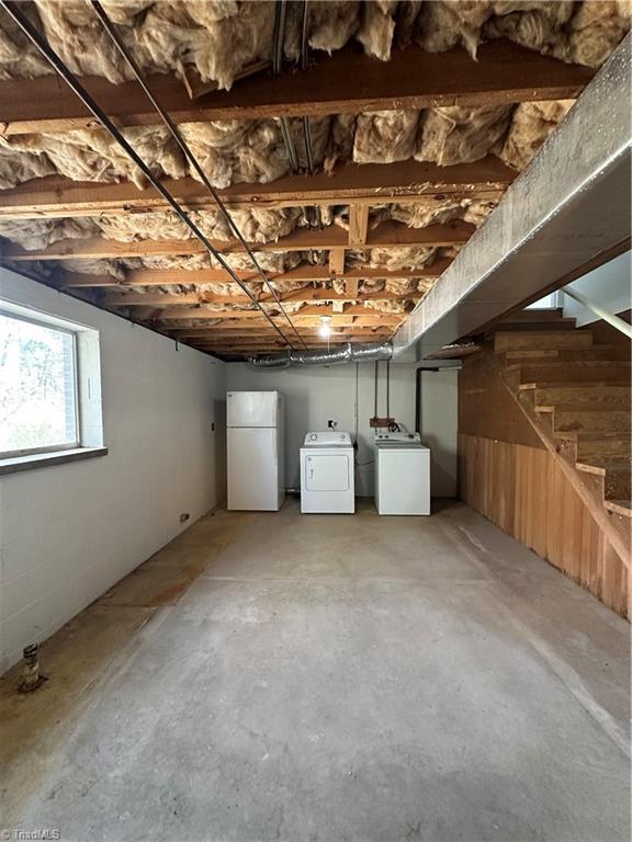 below grade area featuring freestanding refrigerator, separate washer and dryer, and stairs