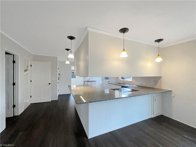 kitchen with decorative light fixtures, dark hardwood / wood-style flooring, light stone counters, kitchen peninsula, and crown molding