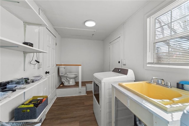 clothes washing area featuring sink, washing machine and clothes dryer, and dark hardwood / wood-style floors