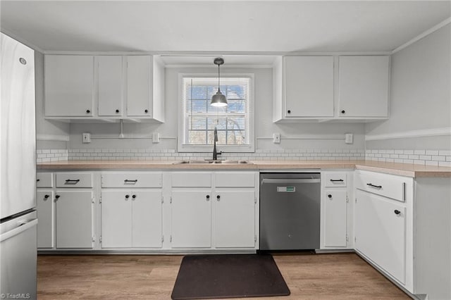 kitchen with pendant lighting, sink, light hardwood / wood-style flooring, appliances with stainless steel finishes, and white cabinets