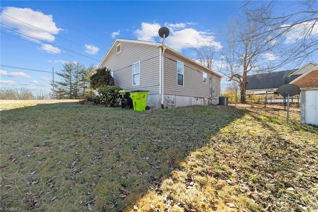 view of side of home with a yard and central AC unit