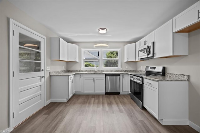 4108 Walker Ave, Greensboro, NC 27407 - kitchen with stainless steel appliances, light wood-type flooring, and white cabinetry
