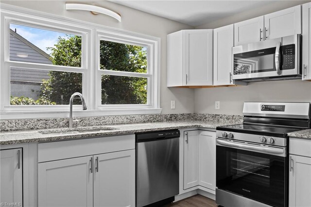 4108 Walker Ave, Greensboro, NC 27407 - kitchen with appliances with stainless steel finishes, white cabinets, light stone counters, and dark wood-type flooring