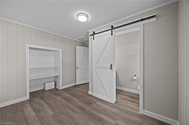 4108 Walker Ave, Greensboro, NC 27407 - unfurnished bedroom featuring ornamental molding, wood finished floors, a barn door, and a closet