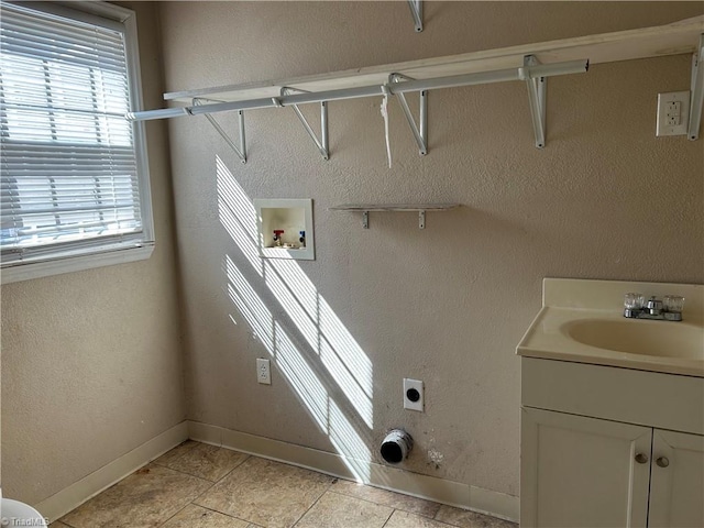 laundry area featuring laundry area, baseboards, hookup for an electric dryer, washer hookup, and a sink