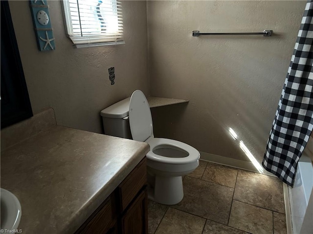 bathroom with a textured wall, toilet, a shower with shower curtain, vanity, and baseboards