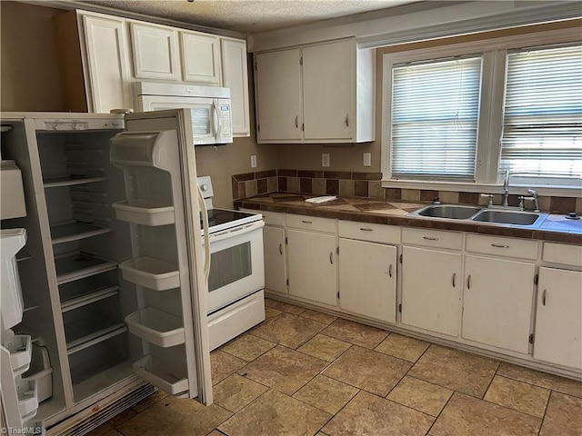 kitchen with tile counters, white cabinets, a sink, a textured ceiling, and white appliances