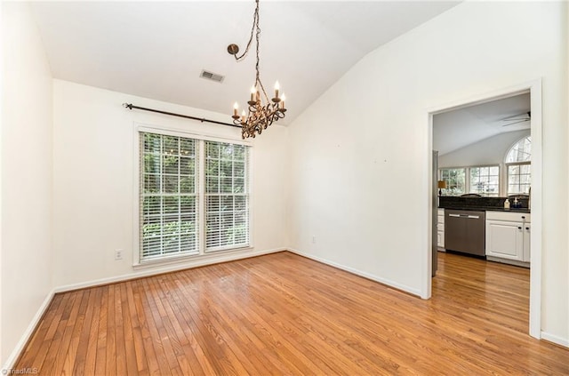 unfurnished dining area featuring a notable chandelier, vaulted ceiling, and light wood-type flooring