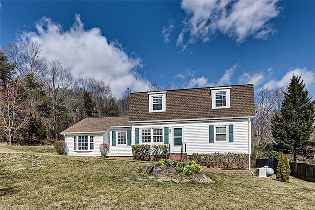 view of front of home featuring a shingled roof, fence, and a front yard