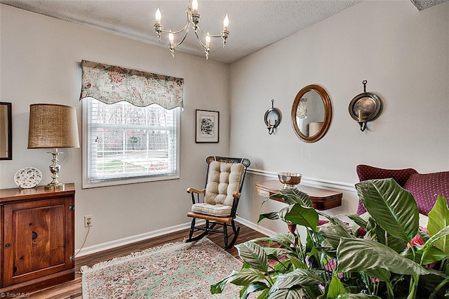 sitting room featuring a notable chandelier, a textured ceiling, baseboards, and wood finished floors