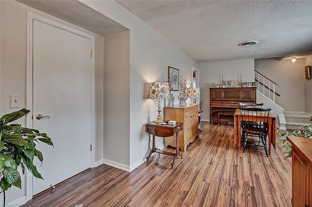 living area featuring baseboards, stairs, visible vents, and wood finished floors