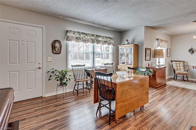 dining area featuring a textured ceiling, baseboards, and wood finished floors