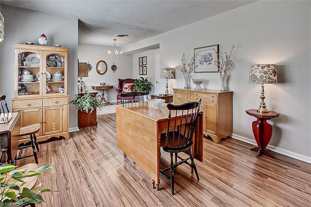 bar featuring an inviting chandelier, a textured ceiling, baseboards, and wood finished floors