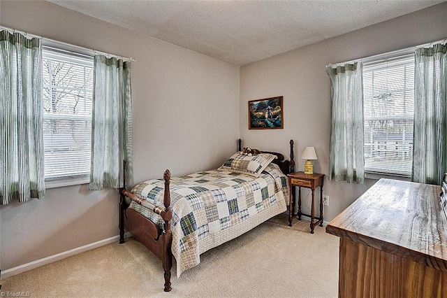 bedroom featuring light colored carpet, a textured ceiling, and baseboards