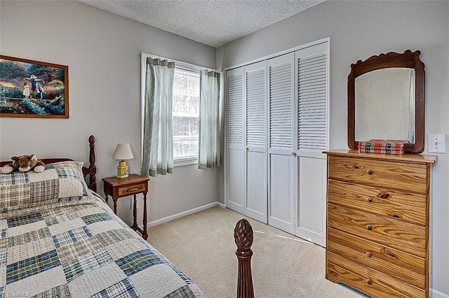 bedroom with a textured ceiling, a closet, baseboards, and light colored carpet